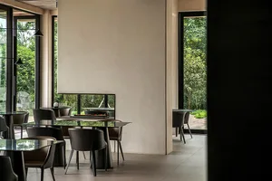 Modern interior of a restaurant featuring glass tables, metal chairs, and wooden flooring.