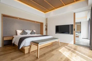 A minimalist bedroom with wooden furniture, a large bed, and a mounted television.