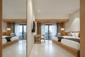 Modern minimalist bedroom featuring wooden furniture and white bedding, with a large window and balcony.