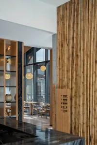 Minimalist cafe interior with wooden seating, glass partitions, and marble finishes.