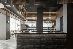 An elegant minimalist restaurant bar with metal accents and a stone counter, featuring industrial lights and modern design el