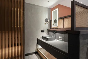 Modern bathroom with a concrete countertop and wood accents, featuring a sleek sink and vanity lighting.