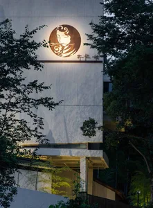 A modern building facade clad in white material, illuminated by ambient lighting.