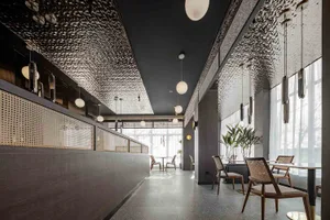 Modern cafe interior with metallic textured ceiling and pendant lights.