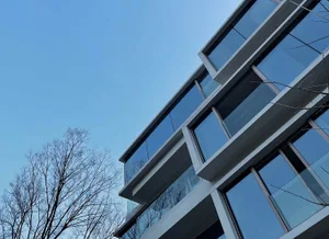 Modern building with glass and concrete exterior against a clear blue sky.