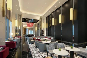 A modern hotel lobby with a sleek design featuring black and white geometric flooring, contemporary seating, and hanging lamp
