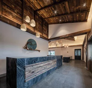 A minimalist lobby featuring a marble reception desk and wooden beams on the ceiling.