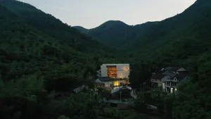 An elegant, modern residential building nestled in a lush green valley.