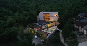 A modern residential space illuminated at night, with concrete structures, glass windows, and warm interior lighting.
