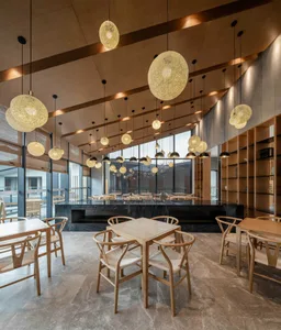 Modern restaurant interior with wooden tables, marble flooring, and woven textile pendant lights