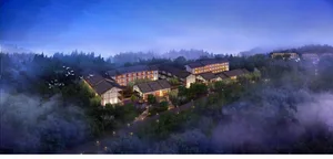 Aerial view of a hotel resort with illuminated rooms and pathways surrounded by trees at dusk.