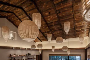 A restaurant interior featuring woven lanterns hanging from a wooden ceiling.
