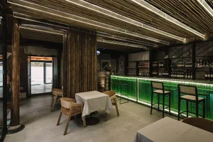 Modernly styled restaurant bar with concrete and green glass materials.