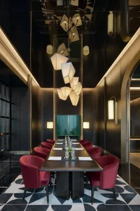 A modern conference room with wooden table, fabric-covered chairs, and glass light fixtures hanging above the table.