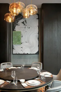 Modern dining room featuring dark wood furniture, white linens, and abstract art hanging above the table.