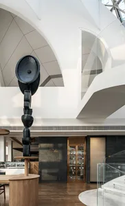 Modern restaurant entry with concrete and stone materials, featuring an abstract black sculpture.