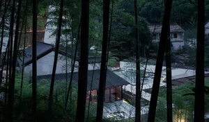 Modern residential house nestled in a forest with striking bamboo and lighting features.