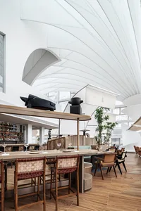 Modern restaurant interior with exposed wood ceiling beams and wooden flooring.