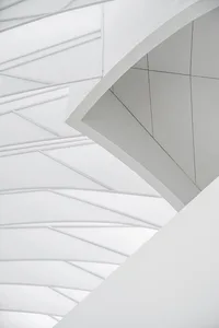 A modern architectural design featuring a white, abstract ceiling with geometric patterns and minimalistic lines.