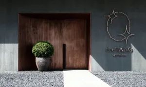 A minimalist entrance with a wooden door and concrete corner, featuring a potted plant.