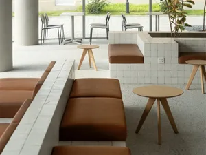 A minimalist coffee shop with fabric seating, wooden tables, and concrete seating areas.