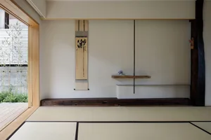 A minimalist living room with a wooden floor and tatami mats, featuring a simple yet elegant design with decorative plants an