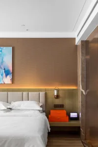 A modern bedroom featuring textured walls, a neatly made bed, a floating nightstand with orange boxes, and a wall-mounted lam