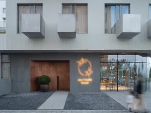 Modern storefront with concrete walls, glass windows, and a neon sign.