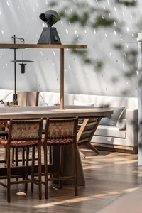 A modern living room featuring a wooden table and chairs, a modern sofa, and a window with a tree view.