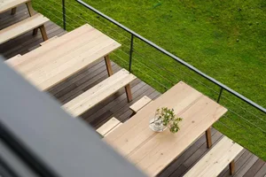 Modern outdoor furniture collection consisting of multiple tables and benches made of light-colored wood with a minimalist de