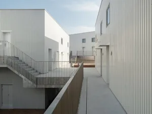 Modern residential buildings with metal cladding and exterior walkways.