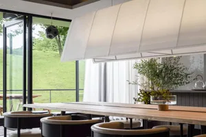 Modern, spacious restaurant interior with large windows showcasing a serene outdoor view, featuring minimalist design, white 
