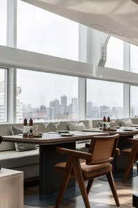Modern restaurant interior featuring wooden seating and cushioned accents.