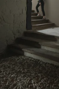 A modern staircase made of wooden steps with a concrete floor in a dimly lit room.