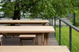 A wooden park bench sitting outdoors with green trees in the background.