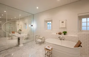 A modern, minimalist bathroom with white subway tiles, a freestanding bathtub, a pedestal sink, and a mirror.
