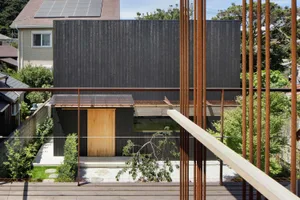 Modern residential building with black wooden walls and a metal roof in a suburban setting.