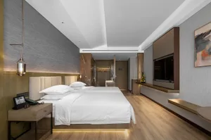 Modern bedroom with white bedding, marble headboard, and leather seating.