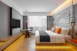 Modern bedroom with minimalist design, featuring a wooden bed platform, warm lighting, and a large window with sheer curtains