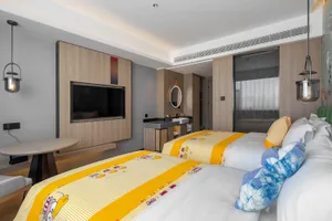 A modern bedroom with a wooden wall, a yellow bedspread, and a flat-screen TV mounted on the wall.