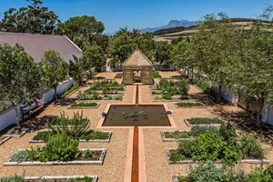 A modern garden featuring natural materials and a water feature surrounded by raised beds.