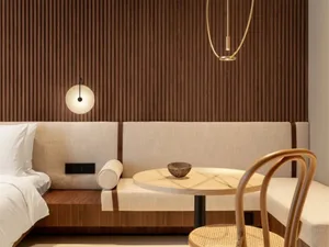 A modern hotel room with wooden paneling, a circular table, and a bed.