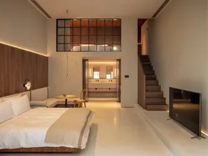 Modern living room with neutral-toned wood and concrete finishes, featuring a minimalist design with a cozy and inviting atmo