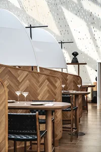 Modern restaurant interior with wooden tables, leather chairs, and contemporary design features.