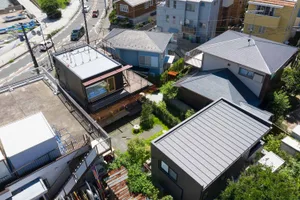 Aerial view of modern residential houses with metal roofing and concrete bases in an urban setting.
