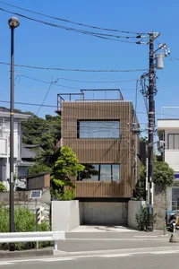 A modern residential building with a wooden exterior, featuring a roof terrace and minimalist design.
