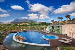 A modern pool setting with stone surroundings and a scenic landscape.