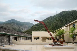 A red crane arm against a backdrop of mountains and buildings under construction