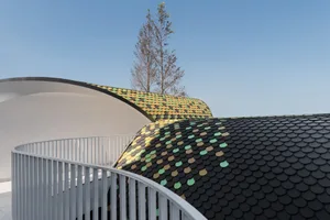A detail view of a multicolored roof with curved architectural elements.