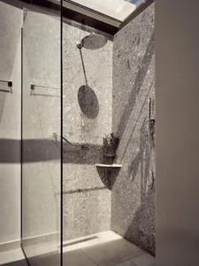 Industrial-style bathroom featuring a terrazzo shower stall with a glass enclosure, providing a modern and rustic ambiance.